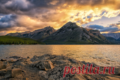 Minnewanka Morning The sun comes forth boldly over Mt. Astley and Banff's Minnewanka Lake.  "Lake Minnewanka ("Water of the Spirits" in Nakoda) is a glacial lake located in the eastern area of Banff National Park.  Dams were built in 1912 and 1941 to supply Banff with hydro-electric power. The most recent dam (1941) raised the lake 30 m (98 ft) and submerged the resort village of Minnewanka Landing that had been present there since 1888. Because of the presence of the subm...