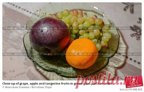 Close-up of grape, apple and tangerine fruits in green glass plate on table Стоковое фото, фотограф Анастасия Усанина / Фотобанк Лори