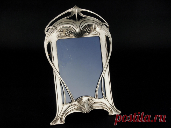 Art Nouveau Polished Pewter Photo Frame - Nouveau Deco Arts Pretty Art Nouveau polished pewter photograph frame from WMF dating from around 1906. Comprising a very pleasingly shaped outline with a stylised, typically Art Nouveau openwork design of sinuous interlocking curves together with a detail of berries towards the top. Glazed and with the original easel type support at the back, it is around 23... View Article