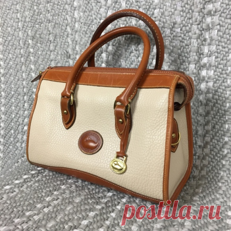 Vintage Dooney & Bourke White Satchel Purse Shop perennialwest's closet or find the perfect look from millions of stylists. Fast shipping and buyer protection. A great vintage Dooney & Bourke piece! This is a white color leather purse that features tan leather details. The interior is all leather lining with one zip pocket and one snap pocket. The exterior is in like new condition with a few light scratches along the top of the tan piece by the zipper but everything else i...