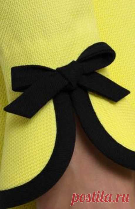 Yellow textured cotton dress with black trim. Upper and lower flounce collar on a stand. Hidden back zip closure. Long sleeves with bows. Without pockets.