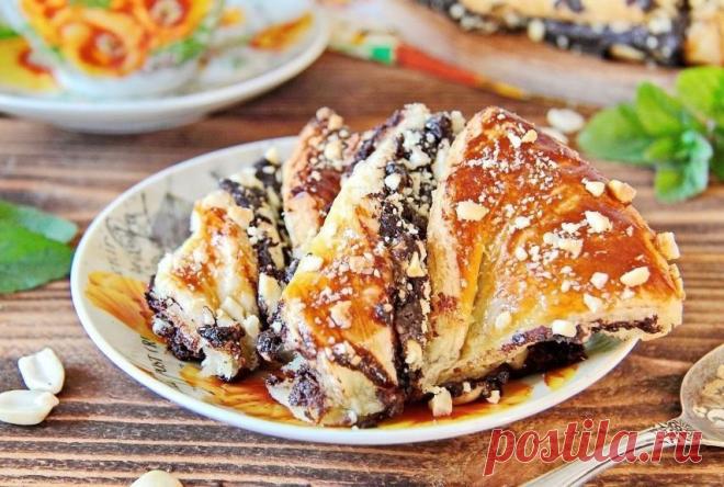 Пирог к чаю с шоколадом

Ингредиенты:

Слоеное тесто — 500 г
Шоколад — 90 г
Молоко — 50 г
Сахар — 50 г
Какао — 2 ст. л.
Сливочное масло — 30 г
Яйцо — 1 шт.
Арахис — 50 г

Приготовление:

1. Подготовьте все необходимые ингредиенты. Тесто заранее достаньте и разморозьте при комнатной температуре.
2. Поломайте шоколад на кусочки, добавьте к нему молоко, какао и сахар. Подогрейте на маленьком огне, постоянно помешивая, доведите до однородного состояния. Уберите шоколадную масс...