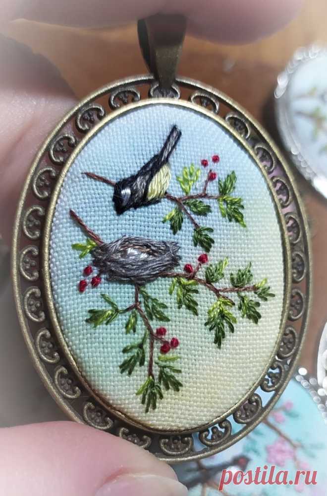 a close up of a person holding a small pendant with birds on it's back