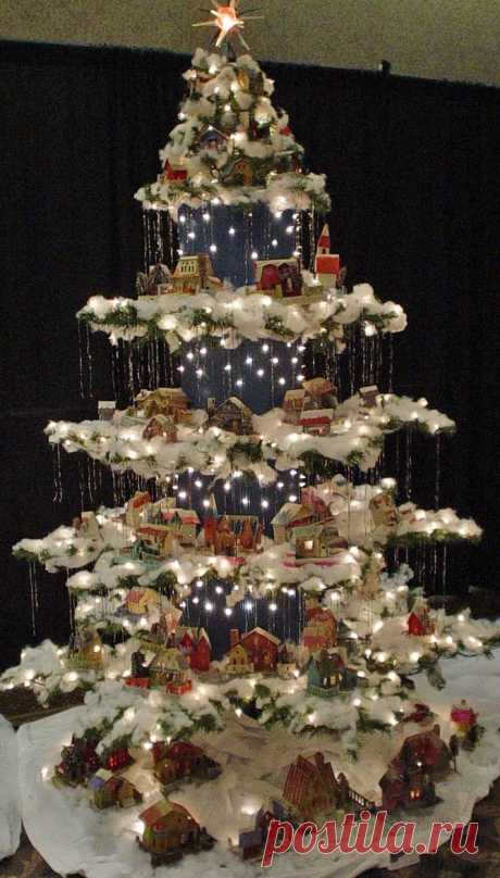 Beautiful Christmas Display. Created from a regular Christmas tree, this " antique paper house village" tree was made by eliminating every 3rd row and bending the 2 remaining rows  to form a layer. Corrugated blue cardboard with lights punched  through, polyester batting snow, and tinsel icicles help finish the look.