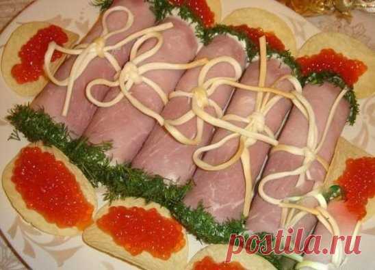 Мясные завитки на Новогодний стол
Ингредиенты:
-сыр
-яйца
-чеснок
-майонез
-копченый сыр
-укроп
-ветчина
Сыр и отварные яйца потереть на крупной терке, добавить измельченный чеснок, майонез и хорошо перемешать.
Ветчину порезать тонкими пластами.
На край каждого кусочка ветчины положить немного начинки и свернуть свиток.
Перевязать свитки полосками сыра. Это копченый сыр типа 