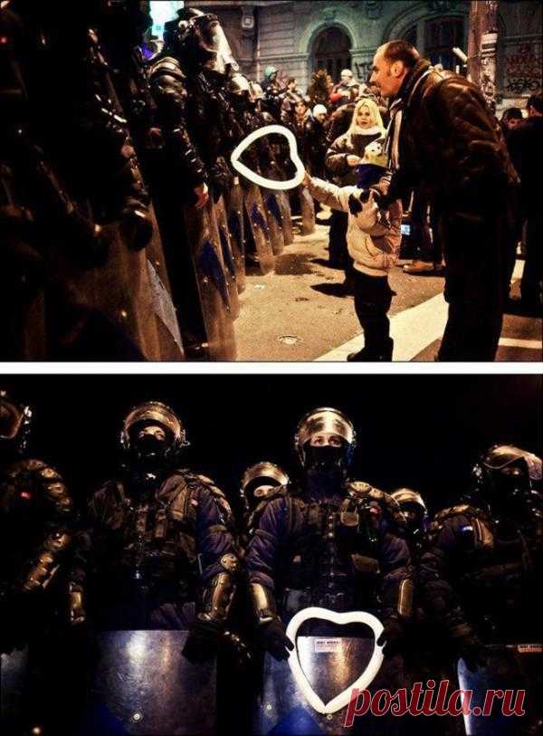 Румынский ребенок вручает воздушный шарик работнику полиции во время протестов в Бухаресте