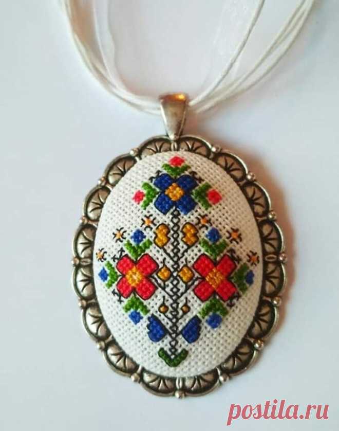 a white necklace with a cross stitch design on it