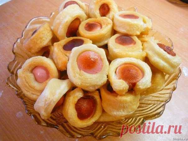 Сосиски в тесте 
 
Ингредиенты: 
-Слоеное тесто — 1 пачка 
-Сосиски - 6 шт 
-Растительное масло для фритюра 
 
Приготовление: 
Готовое слоеное тесто слегка раскатываем и разрезаем на 6 частей. В каждую плотно заворачиваем по одной сосиске. Край защипываем и приминаем. 
Такую сосиску в обертке из теста разрезаем на колечки толщиной 1-1.5 см 
В сковороде разогреваем примерно пол литра растительного масла. Кладем сосиски и обжариваем с 2-х сторон 
Сытно, быстро и просто. 
Приятного аппетита!