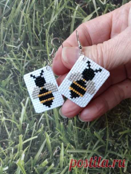 a person holding two small beaded earrings in their hand on some grass and grass