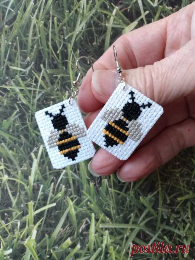 a person holding two small beaded earrings in their hand on some grass and grass