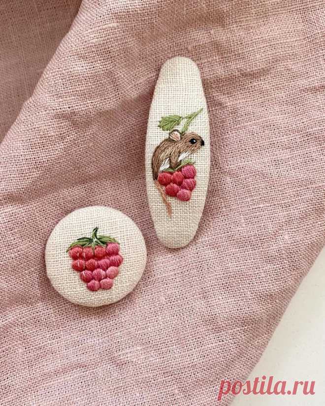 two small white rocks with red berries on them sitting on a pink cloth covered surface