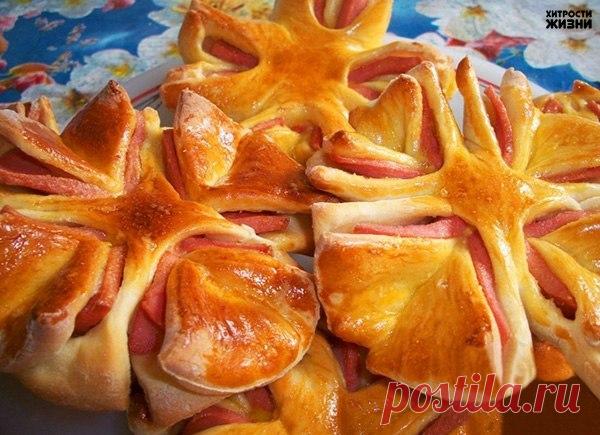 Колбасные цветочки к завтраку

1. Готовое тесто раскатать в не очень тонкий пласт и подходящей формочкой (например, пиалой) вырезать четное количество тестяных кружков в размер кружочков нарезанной колбасы. 
2. Между каждыми двумя тестяными кружочками поместить кружочек из колбасы. 
3. Сделать по кругу 8 радиальных надрезов на одинаковом расстоянии друг от друга и несколько отступая от центра, чтобы центральная часть осталась целой. 
4. Каждые 2 полученных при разрезании с...