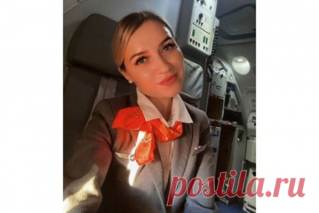 Российская стюардесса сделала фото в униформе и восхитила иностранцев. Стюардесса российской авиакомпании «Азимут» сделала фото в самолете и восхитила иностранцев. На фотографии видно, что бортпроводница одета в фирменную униформу перевозчика: на ней белая рубашка, темно-серый пиджак и юбка. Образ девушки дополнен оранжевым шейным платком, жемчужными серьгами и убранными в пучок волосами.