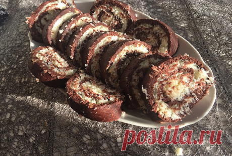 Рулет с кокосовой начинкой без выпекания
ИНГРЕДИЕНТЫ
Вода 100 мл
Сахар 20 г
Кокосовая стружка 80 г
Сливочное масло 80 г
Какао 2 столовые ложки
Печенье 200 г
Сахарная пудра 20 г
 ПРИГОТОВЛЕНИЕ:
1. Печенье измельчить в крошку, смешать с какао. В горячей воде растворить сахар, остудить. Понемногу добавить воду в печенье и перемешивать, пока не получится вязкое тесто.
2. Кокосовую стружку смешать с маслом и пудрой.
3. Массу из печенья раскатать на пищевой пленке в прямоугольны...