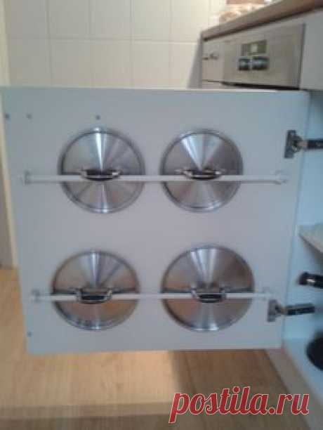 Gordijnroetjes aan de binnenkant van een keukenkastje geschroefd. Pannendeksels ertussen. Blijven hangen aan de handgreep.