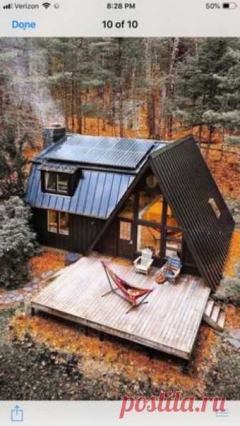 A frame house with barn style extension in black in woods