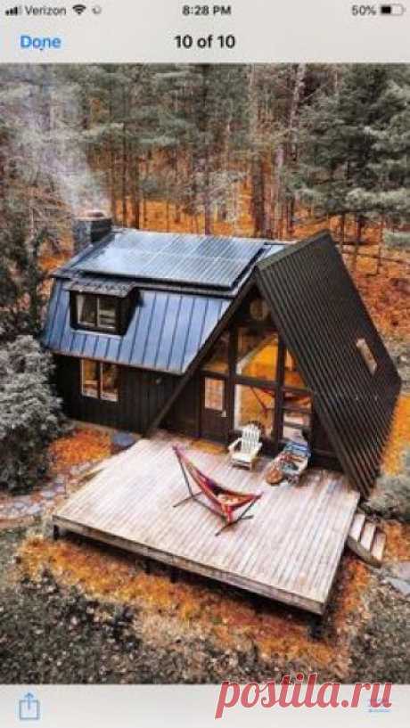 A frame house with barn style extension in black in woods