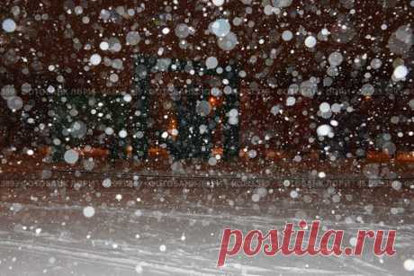 A snowstorm in progress, with snowflakes falling from the sky and covering the ground. The scene is dark and moody, with the snow creating a sense of isolation and stillness. Парк имени 50-… (2016 год) Редакционное фото, фотограф Ilaronsia / Фотобанк Лори