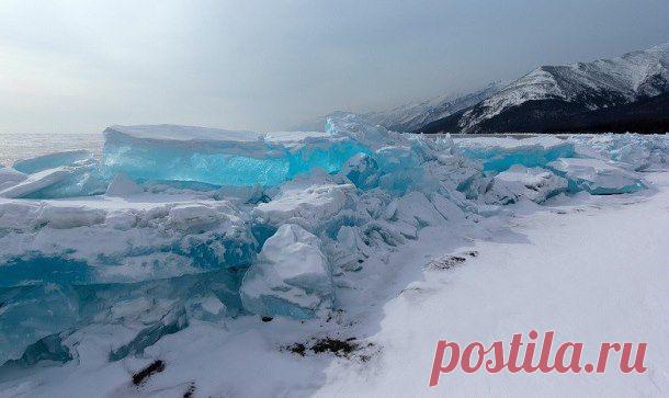Невероятный бирюзовый лёд озера Байкал
Озеро Байкал само по себе замечательно даже без ярких ледяных чудес. Эти 31 722 км водной глади расположены в юго-восточной Сибири. Байкал – самое древнее озеро на Земле, по одной из версий оно образовалось 25 миллионов лет назад. Дно этой гигантской впадины лежит на 1186 м ниже уровня моря, а расстояние от поверхности воды до наинизшей исследованной точки достигает 1642 м. Байкал – самое глубокое озеро на планете.