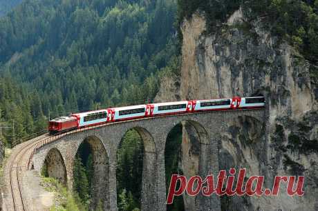 Ретийская железная дорога Ретийская железная дорога (Rhätische Bahn)  – сеть узкоколейных железных дорог в Швейцарии, известная туристическая достопримечательность, объект всемирного наследия ЮНЕСКО и одна из самых живописных дорог в мире. Путешествие по Ретийской железной дороге – полноценная экскурсия по отдаленным уголкам Швейцарии и самым труднодоступным уголкам Альп. Протяженность железной дороги – 384 километра (часть проходит по территории Италии), ширина …