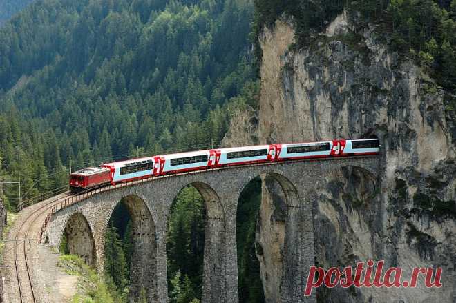 Ретийская железная дорога Ретийская железная дорога (Rhätische Bahn)  – сеть узкоколейных железных дорог в Швейцарии, известная туристическая достопримечательность, объект всемирного наследия ЮНЕСКО и одна из самых живописных дорог в мире. Путешествие по Ретийской железной дороге – полноценная экскурсия по отдаленным уголкам Швейцарии и самым труднодоступным уголкам Альп. Протяженность железной дороги – 384 километра (часть проходит по территории Италии), ширина …