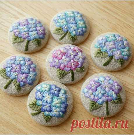 six hand embroidered flowers are sitting on a wooden surface