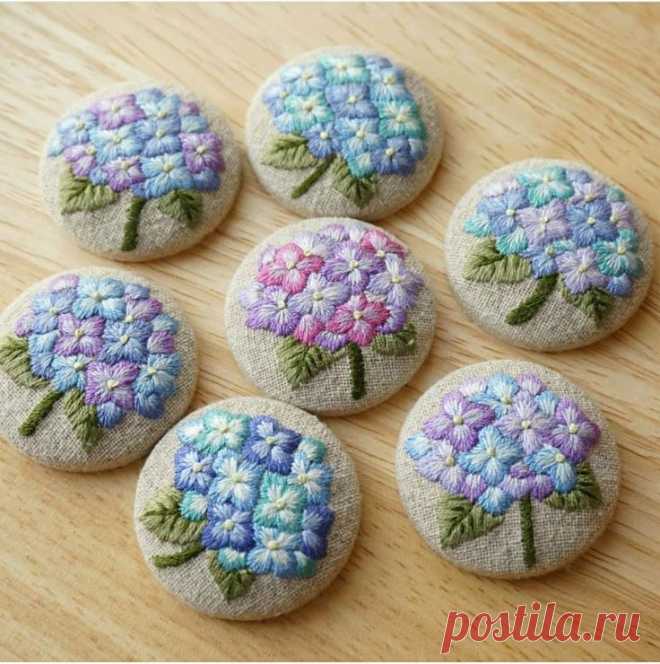 six hand embroidered flowers are sitting on a wooden surface