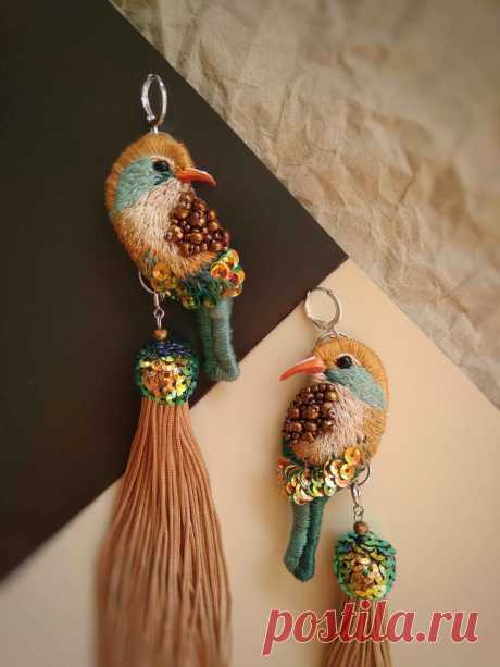 two birds are hanging from tassels on the wall