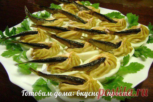 Шпротинки в яйце

Состав:
-яйца
-чеснок
-шпроты

Отварить яйца, разрезать пополам, вынуть желток. 
В миску сложить желтки, тертый сыр немного, 2 зубчика чеснока, ложку томата. 
Налить масло с шпрот и пару ложек майонеза и взбить блендером в крем. 
Крем отсадить через корнетик с насадкой в половинки белка яиц и в каждую погрузить шпротинку.