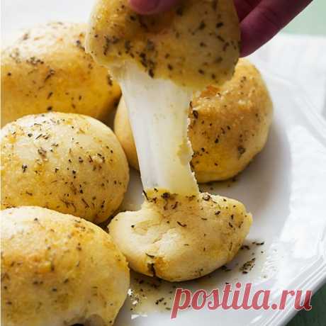 Сырная серия:
Сырные бомбочки
Разогрейте духовку. Нарежьте заранее приготовленное тесто в форме квадратных печений. Положите в центр каждого из них кубик твердого сыра, оберните вокруг него тесто и скатайте в форме шара. В миске расплавьте в микроволновой печи сливочное масло с чесноком. В отдельной миске смешайте петрушку и тертый сыр пармезан. Окуните шарики сначала в масло, потом в сырную смесь и выложите на противень. Выпекайте шарики 10-12 минут, пока они не подрумянятся.