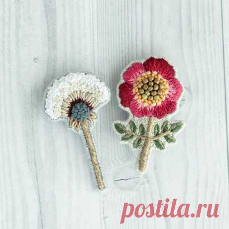 two crocheted flowers sitting next to each other on top of a white table