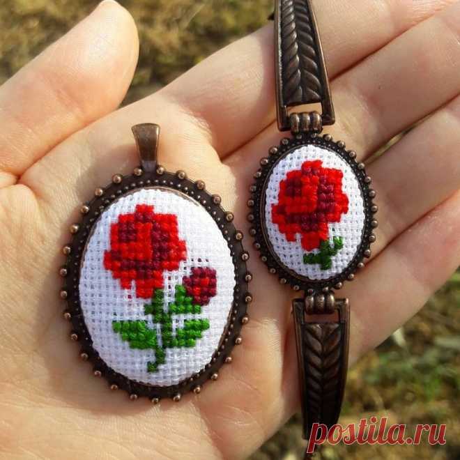 two cross stitch roses are being held by someone's hand in their left hand
