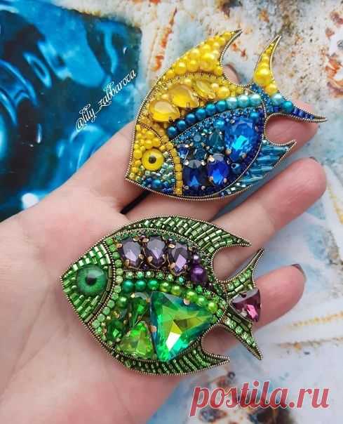 two colorful fish brooches sitting on top of each other's palm hand