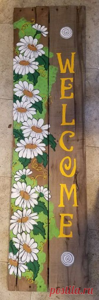 A welcome wood pallet sign with daisies painted on it