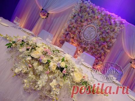 Стена из живых цветов и драпировка из ткани, очень необычно смотреться в качестве заднего фона торжественного мероприятия в оформление свадебного зала в сиреневом цвете