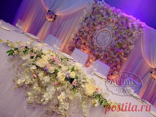 Стена из живых цветов и драпировка из ткани, очень необычно смотреться в качестве заднего фона торжественного мероприятия в оформление свадебного зала в сиреневом цвете