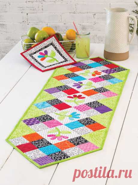 EXCLUSIVELY ANNIE'S QUILT DESIGNS: Flower Patch Table Runner Pattern This table runner features a row of appliqued flowers bordered with colorful patchwork. The coordinating pot holder has a single appliqued flower. Finished size is 50 1/2" x 14 1/2".