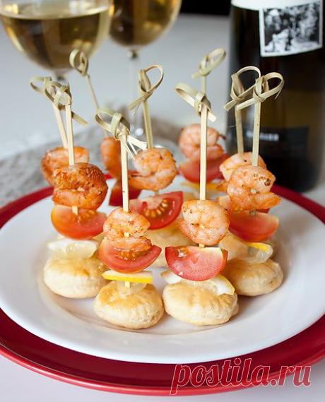 Канапе из креветок с помидорками черри. Фуршетная закуска. Канапешки простые и вкусные. Кстати этот рецепт придется тем, кто будет готовить для того же стола волованы - там остается определенное количество выпеченных бесхозных слоеных основ. При приготовлении этой закуски можно заменить помидоры другими свежими овощами по вкусу –  огурцом или сладким перцем. Ингредиенты: 250г готового слоеного теста,  24 крупных креветки, 12 помидорок черри, половина лимона,  соль и молотый черный перец по вкусу