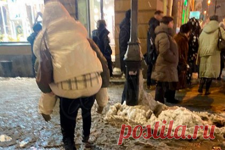 Россияне начали носить друг друга на руках. Жители Санкт-Петербурга начали носить друг друга на руках из-за появившейся на улицах города слякоти. Фото были сделаны на угле Невского и Марата. На них мужчина помогает девушке перебраться на другую сторону тротуара, покрытого толстым слоем заледеневшей слякоти. Россиянка находится на спине помощника.