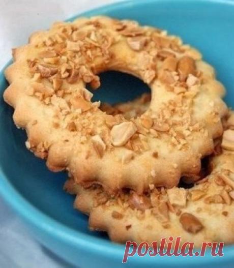 ПЕСОЧНЫЕ КОЛЬЦА С АРАХИСОМ.
15 штук диаметром 8см
Ингредиенты:
200г масла
130г сахарной пудры
350г муки
1 яйцо
1\2 ч.л. ванильной эссенции (или пол пакетика ванильного сахара)
1\4 ч.л. соли (растолочь)
1\2 ч.л. разрыхлителя.
1 желток для смазки
65г орехов для посыпки
противень
формочки диаметром 8 см и диаметром 2см
Приготовление: 
Сложите все продукты кроме муки в миску. 
Взбить миксером (1-2 минуты)
Всыпьте муку и быстро замесите тесто. Остудите его в холодильнике, оптимальная температура