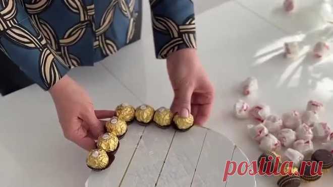 Упаковать конфеты в букете с розами.