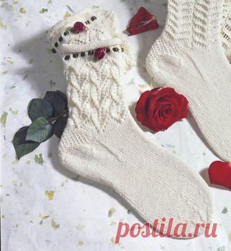 Белые носки с розочкой 
Красивый узор паголенка и планка-рулик, подчеркнутая продернутой атласной лентой с розочкой, делают эти носки очень женственными и романтичными. 

РАЗМЕРЫ 
36/37 (38/39) 

ВАМ ПОТРЕБУЕТСЯ 
Пряжа (75% натуральной шерсти, 25% полиамида; 420 м/100 г) – 100 г натурально-белой; чулочные спицы № 2,5; ок. 50 см атласной ленты болотно-зеленого цвета шириной 6 мм, 2 бордовые розы из атласа диаметром по 3 cм; прозрачные швейные нитки. 

УЗОРЫ И СХЕМЫ 

ЛИЦЕВА...