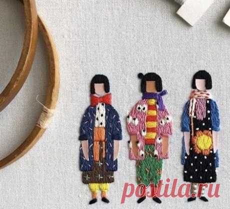 three embroidered dolls are sitting next to a pair of scissors