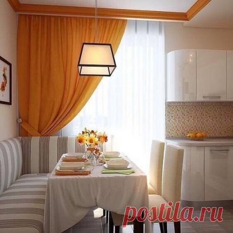 Светлая кухня с акцентом на яркие оранжевые шторы. И вполне уютная обеденная зона с диванчиком