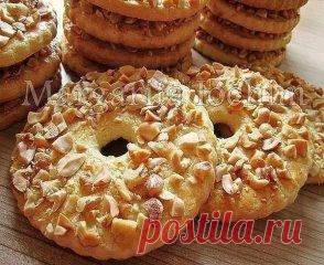 Песочные кольца с орехами
Тесто: 
250 г сливоч. масла (холодного) - порезать кусочками 
150 г сахара 
1 яйцo (среднее) 
1 п. ванил. сахара (8 г) 
1 ч. л. с горкой разрыхлителя (5 г) 
2,5 ст. муки (400 г) - просеять 
Дополнительно: 
1 ст. жареного арахиса (160 г) - порубить не мелко ножом 
Для смазывания: 
1 желток + 2 ст. л. молока - перемешать вилочкой 
В чашку выкладываем масло, сахар, яйцо, ванил. сахар и разрыхлитель - слегка перемешиваем.
Постепенно подсыпая муку, замешиваем песочное те