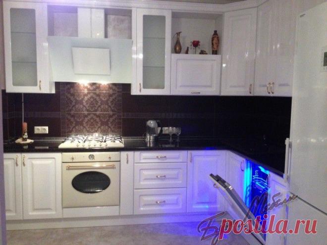 Вариант угловой кухни с фасадами МДФ эмаль глянец белая в классическом стиле с полно встраиваемой посудомоечной машиной, отдельно стоящим холодильником и наклонной вытяжкой.