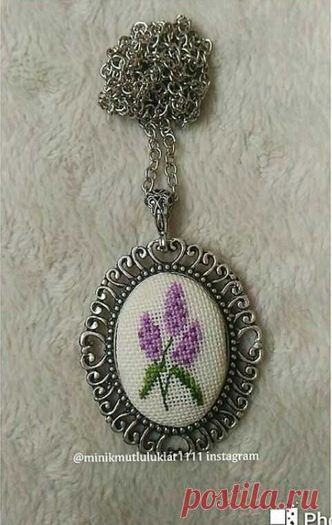 a purple flower is in the center of a silver chain pendant on a white background