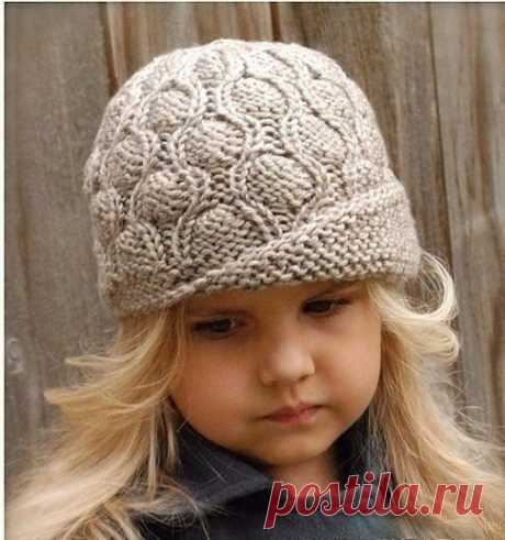 Шапочка-шляпка для девочки спицами .

Окружность шляпки — 50 (55) см.
Для вязания будут необходимы: пряжа серая и бордовая – по 1 мотку 
(шерсть 100%, 182 м/115 г); круг. спицы — 4 мм (0,4м);
чулочные обоюдоострые спицы — 4 мм;
маркеры для петель.

Шляпку вяжем по кругу лиц. гладью. Отворот выполняем укороченными рядами плат. вязкой. Кайму вяжем плетеным узором.
Плетеный узор.
Ряд 1 и 3: лиц. п.;
Ряд 2: * лиц., снимаем п. как изн., нить перед работой; повторяем от * 
до ко...