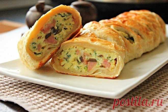 Слойка с яичницей

Ингредиенты:

Лист слоеного теста — 1 шт.
Яйца куриные — 6 шт.
Шампиньоны — 200 г
Ветчина — 200 г
Сыр — 100 г
Укроп — 1 небольшой пучок
Сливочное масло — 1 ст. л.
Соль, перец — по вкусу
Яйцо (для смазывания) — 1 шт.

Приготовление:

1. В сковороде сначала обжариваем грибы.
2. Режем кубиками ветчину.
3. Добавляем к грибам и жарим еще около 3 минут.
4. Сыр трем на терке.
5. Укроп мелко нарезаем.
6. Яйца слегка взбиваем и перемешиваем с сыром и зеленью.
7. ...