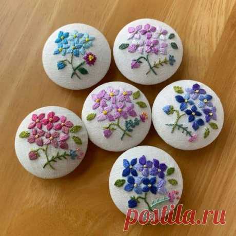 six embroidered buttons with flowers on them sitting on a wooden table next to each other
